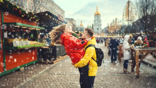 Joven pareja divirtiéndose juntos en un día de nieve y luciendo feliz y guapo joven portando a su novia mientras caminaba por la calle.. —  Fotos de Stock