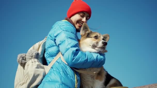 Любящая молодая женщина гладит и обнимает милую собаку Корги в солнечный весенний день — стоковое видео