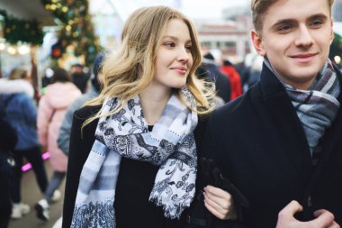 Genç ve güzel sarışın bir çift kalabalık içinde şehir sokaklarında yürüyor..