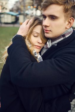 Genç bir adam kız arkadaşını nazikçe kucaklıyor, birlikte rahat hissediyordu..