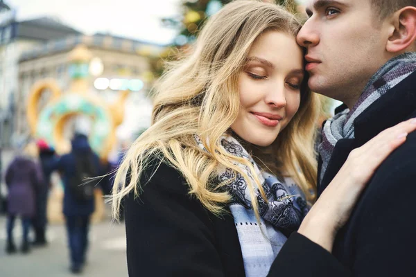 Retrato de la atractiva mujer rubia vestida de negro abrazando a su novio con los ojos cerrados.. —  Fotos de Stock