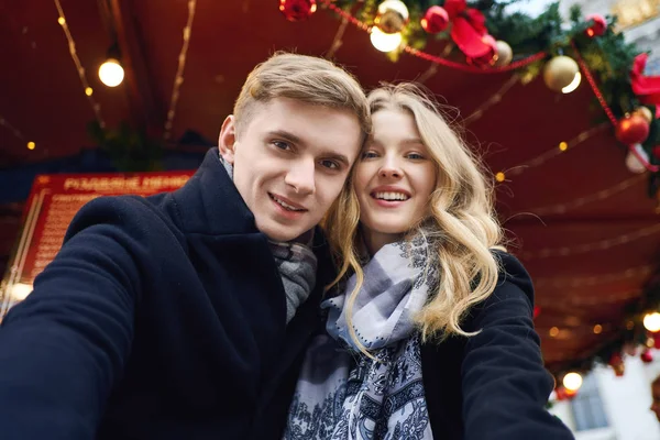 Elegante coppia romantica innamorata fare selfie, guardando la fotocamera e in posa su decorazioni festive sfondo . — Foto Stock