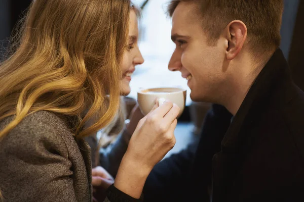Portret de closeup al cuplului tânăr fericit stând pe fereastră în cafenea, zâmbind, râzând și bând cafea . — Fotografie, imagine de stoc