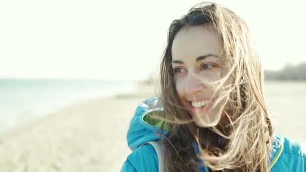 Close up slow motion portrait of pretty brunette woman outdoors on beach wind blowing hair — Stock Video