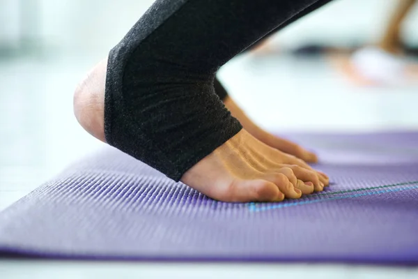 Primer plano de piernas de mujer en yoga violeta o colchoneta de fitness en interiores, haciendo pose de yoga . — Foto de Stock
