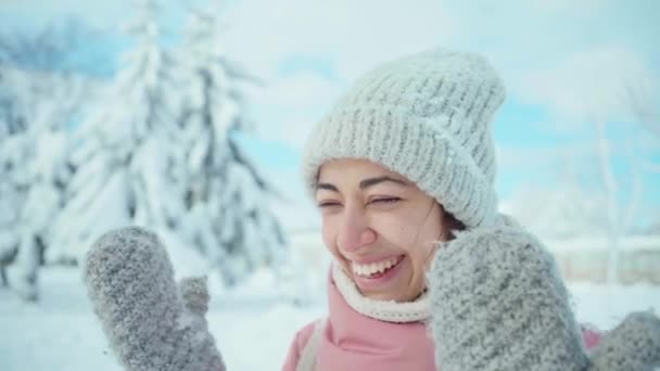 Emotivní portrét šťastné smějící se dívky v teplé růžové bundě procházky ve zasněženém zimním parku v zamrzlém slunečném dni — Stock video