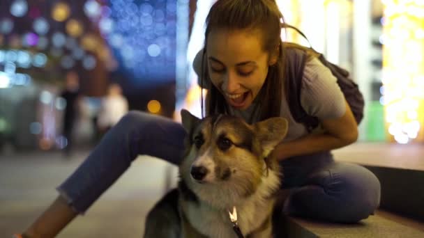 Любящая молодая женщина гладит и обнимает милую собаку Корги на открытом воздухе — стоковое видео