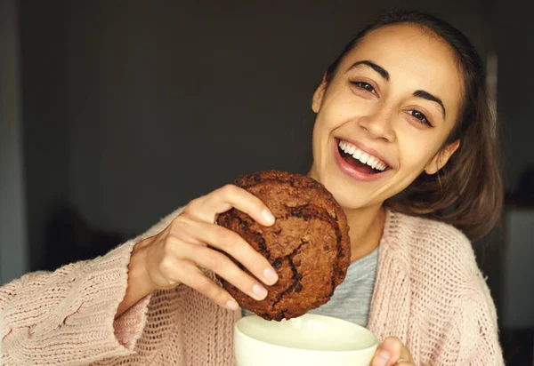 Hübsche Frau hält großen Schokoladenkeks und große Tasse Tee, lacht und lächelt in die Kamera — Stockfoto