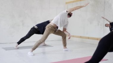 Yoga yapan, Genişletilmiş Angle yoga pozunda duran bir grup insan.