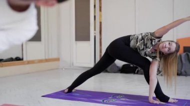 İçeride yoga yapan bir grup genç sporcu. Önplandaki çekici sarışın kadın.