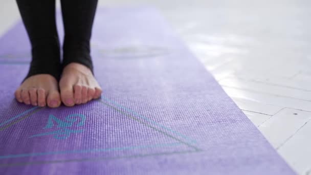 Nahaufnahme von Frauenbeinen auf violettem Yoga oder Fitnessmatte im Innenraum, in Yoga-Pose. — Stockvideo