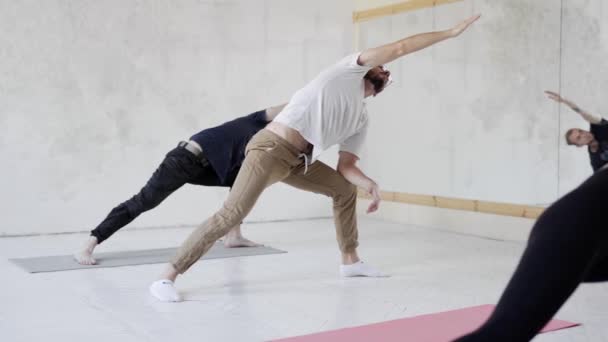 Slow motion Grupp människor som utövar yoga, stående i Extended Side Angle yoga pose — Stockvideo