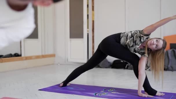 Gruppe junger Sportler, die Yoga im Innenraum praktizieren. attraktive blonde Frau im Vordergrund — Stockvideo