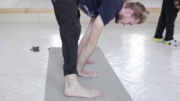 Slow motion jonge knappe man oefenen yoga in licht yoga klasse — Stockvideo
