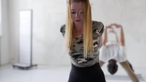 Grupos de jóvenes en cámara lenta en clase de yoga practicando yoga y haciendo ejercicios de estiramiento para piernas y espalda . — Vídeo de stock