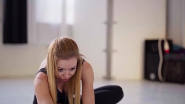 Atractiva mujer flexible en ropa deportiva negra trabajando en estudio de yoga, haciendo estiramiento de nuevo en la estera — Vídeos de Stock