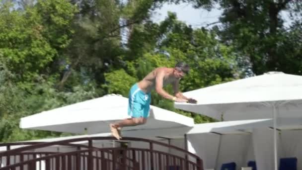 Homem atlético bonito pulando para a piscina e emerge — Vídeo de Stock