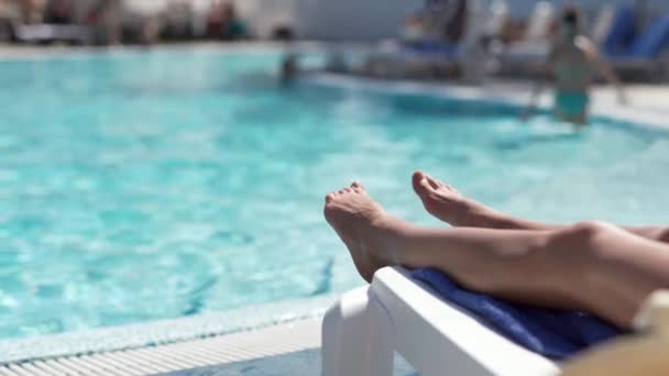 Vrouwelijke benen van onherkenbare vrouw ontspannen bij het zwembad in luxe hotel spa — Stockvideo