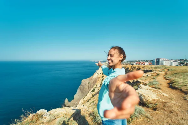 Портрет щасливого молодого, що стоїть на краю скелі з прекрасним видом на море, безтурботна свобода з відкритими руками, слідуйте за мною концепцією . — стокове фото