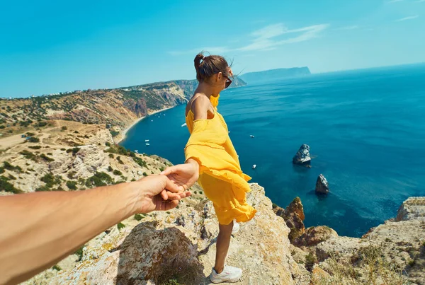 Suivez-moi, première personne vue d'une voyageuse taquinée debout sur le bord d'une falaise, tenant la main de son copain — Photo