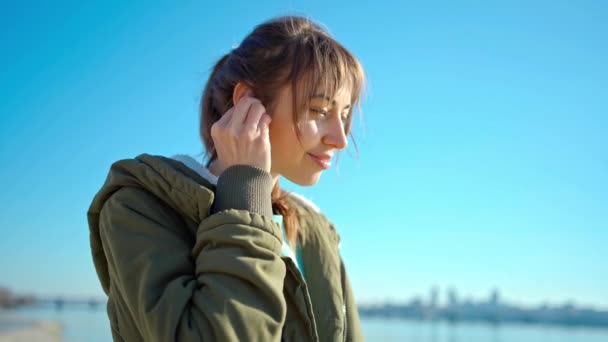 Ung vacker kvinna gör dubbel kran Använda trådlösa hörlurar utomhus — Stockvideo