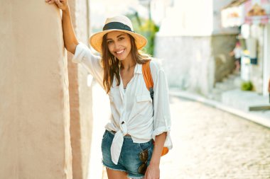 Portre neşe dolu turist kadın eski şehrin eski sokaklarında duvarın önünde duruyor, Avrupa 'da tek başına tatilin tadını çıkarıyor..
