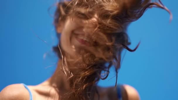 Super slow motion close up retrato de jovem alegre menina tremendo voando cabelo, olhando para baixo para a câmera e sorrindo — Vídeo de Stock