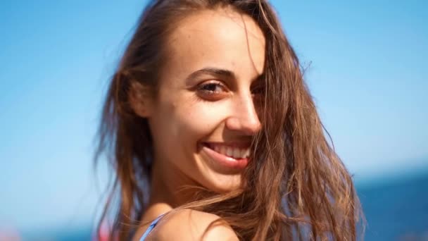 遅い動きを閉じます美しい日焼けした女性は、カメラの笑顔で振り返ってビーチを歩いて — ストック動画
