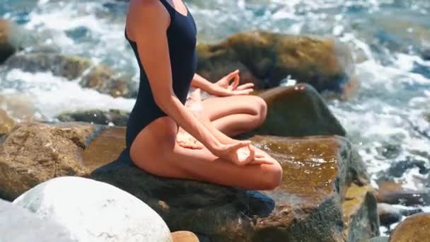 Krásná mladá sportovní žena meditující v blízkosti moře v létě slunečný den. — Stock video