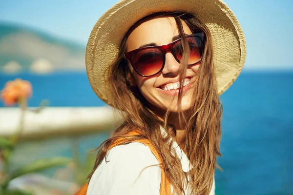 Close-up helder portret vrolijke vrouw toerist in stro hoed en zonnebril op zoek naar camera met glimlach. — Stockfoto