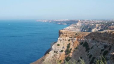 Mavi denizin üzerinde yüksek kireçtaşı uçurumları ve berrak mavi gökyüzü olan deniz manzarası.