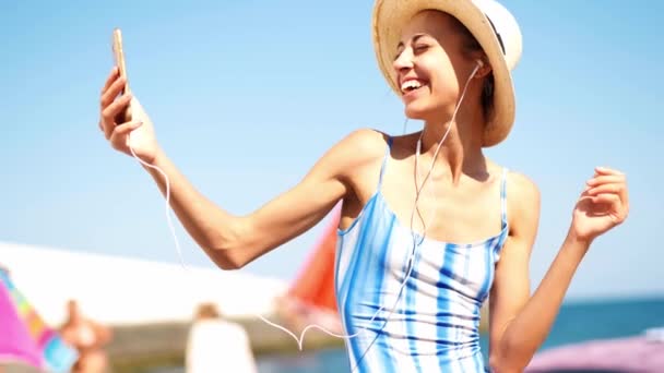 Joyeuse belle femme en maillot de bain et chapeau de paille faisant selfie ou appel vidéo, souriant à la caméra — Video