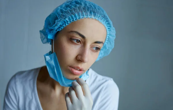 Yong médico em cap e máscara facial sentindo-se para baixo, exausto, frustrado, muito cansado após o trabalho no hospital . — Fotografia de Stock