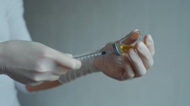 Hastanede hemşirelerin ellerinde şırınga ve aşı şişesi var..