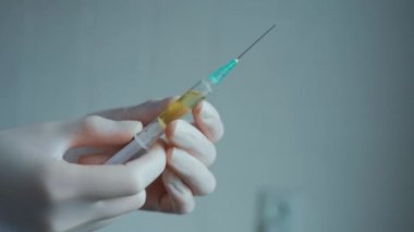 Doktor elinde enjeksiyon iğnesi tutuyor..