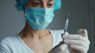 Kadın hemşire elinde şırıngayla eldivenlerinin içinde ilaç taşıyor..
