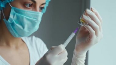 Kadın doktor elinde şırınga ve aşı tutan eldivenleri teslim etti..