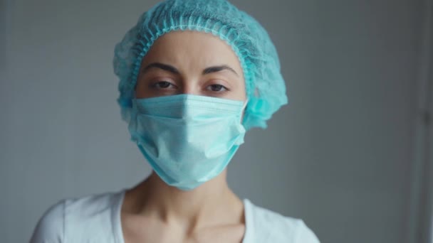 Retrato de uma médica ou enfermeira que usa boné médico e máscara facial — Vídeo de Stock