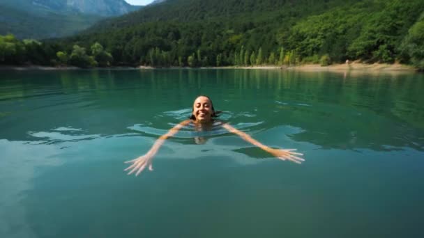 Schöne schlanke sexy glückliche Frau in blauer Badebekleidung entspannen, schwimmen und genießen frisches Wasser im Bergsee an heißen, sonnigen Sommertagen. — Stockvideo