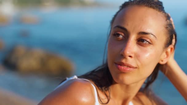 Όμορφη αισθησιακή μαυρισμένη λατινική γυναίκα κάθεται σε roks στην τροπική παραλία — Αρχείο Βίντεο