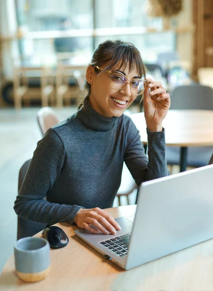 Gözlüklü zeki bir kadın kameraya gülümsüyor, çalışma alanında çalışmaktan zevk alıyor, kablosuz internet kullanıyor. Kadın dizüstü bilgisayarın önünde oturuyor. Okuma, öğrenme, uzaktan çalışma, serbest çalışma.