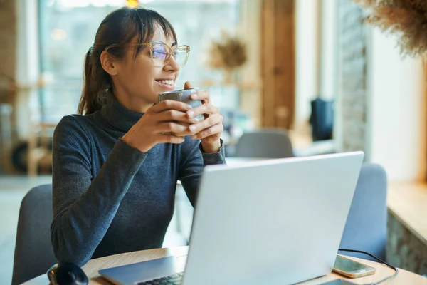 Houkutteleva Hymyilevä Nainen Joka Nauttii Kahvista Työskennellessään Kahvilassa Tai Coworking — kuvapankkivalokuva