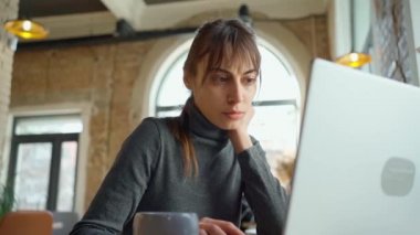 Kafede çalışan konsantre genç kadın, uzaktan çalışma, dizüstü bilgisayar ve kablosuz internet kullanımı.