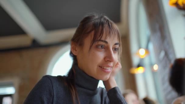 Retrato de mujer joven inteligente en vasos bebiendo café, sonriendo a la cámara, disfrutando de estudiar en el espacio de coworking o cafetería, utilizando wifi y computadora portátil — Vídeo de stock