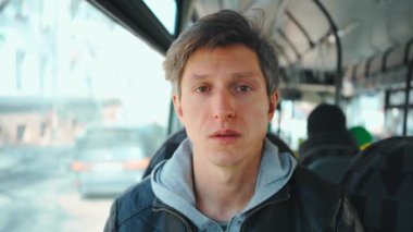 Otobüste otururken orta yaşlı Avrupalı bir adam hasta görünüyor. Hasta erkek, koruyucu maskesi olmadan toplu taşıma aracında kameraya bakıyor..