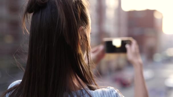 SLOW MOTION: achteraanzicht dolly zoomen schot onherkenbare vrouw staande op zonsondergang stad straat achtergrond — Stockvideo