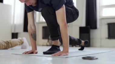 Siyah spor kıyafetli adam yoga yapıyor.