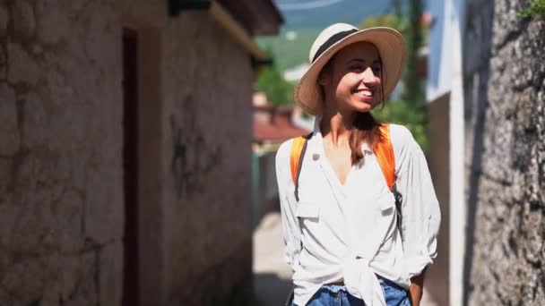 Alegre joven turista en camisa blanca y sombrero de paja caminando en la antigua calle — Vídeos de Stock