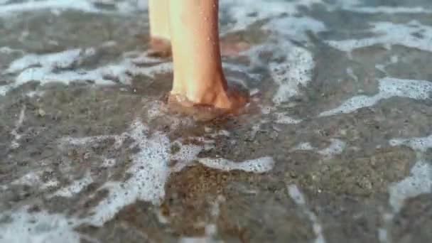 Slow motion närbild barfota kvinnliga ben på stranden med rullande vågor. — Stockvideo