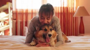 Evde köpeğiyle gülümseyen kadın, esneyen komik köpek Welsh Corgi 'ye sarılıyor.